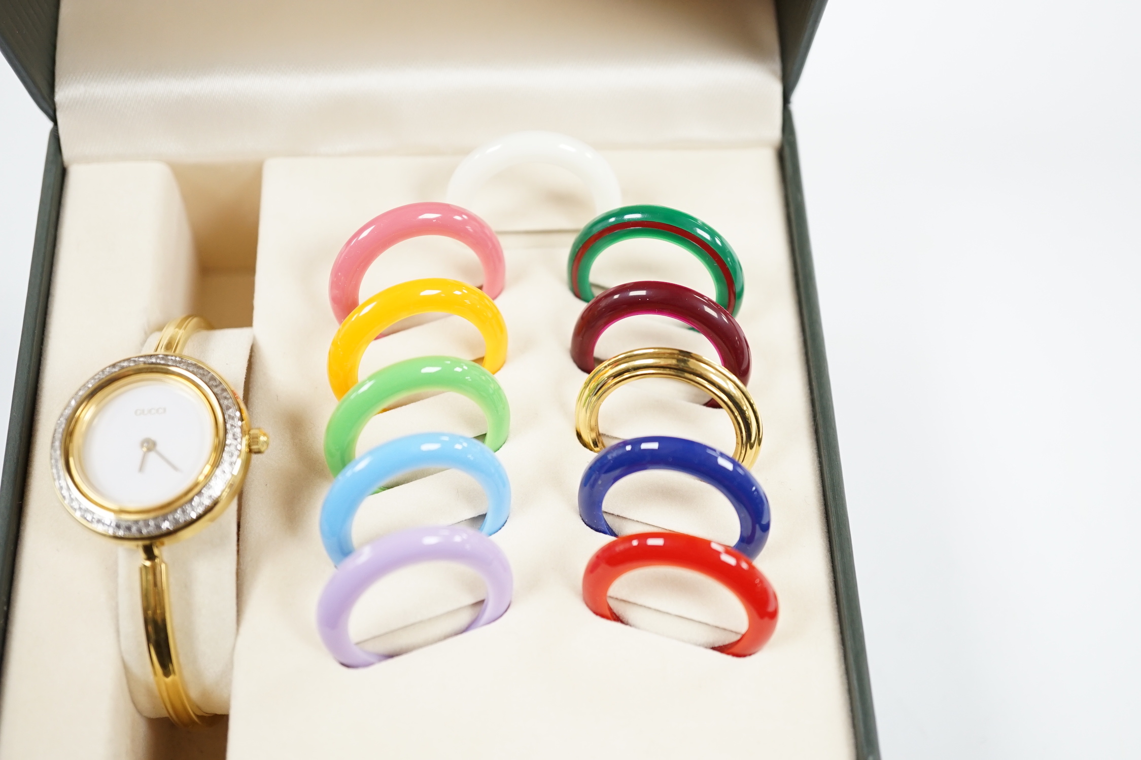 A lady's modern gilt Gucci quartz bangle wrist watch, with twelve interchangeable bezels, in original Gucci box.